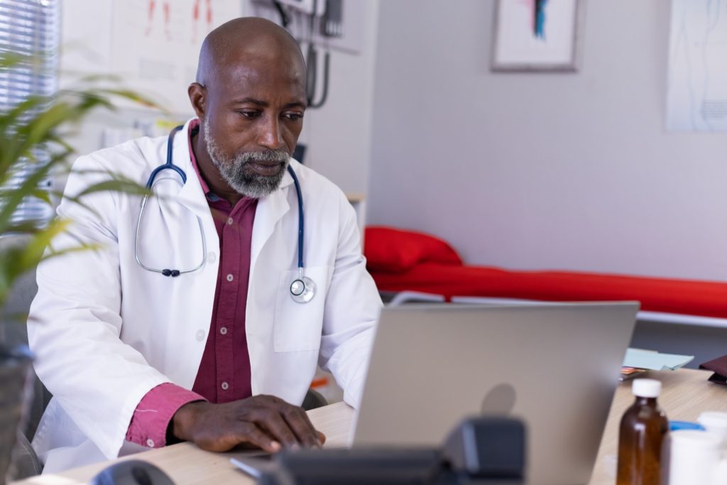 male doctor sitting at desk and using laptop for training