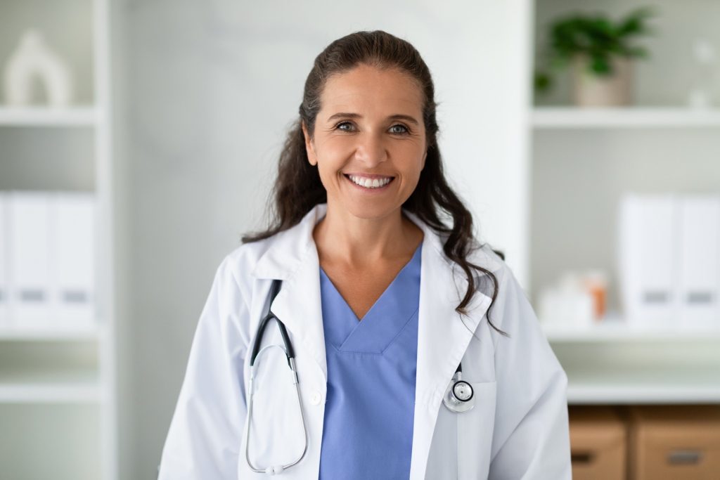Portrait of cheerful mature woman doctor posing in clinic